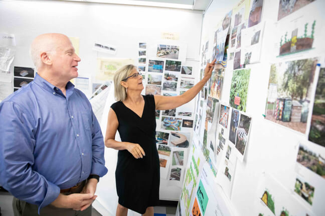 Woman and man looking over a wall of photos.